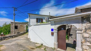 A narrow street with a white building featuring a brown door and a stone wall. - House Katica (Grizane)