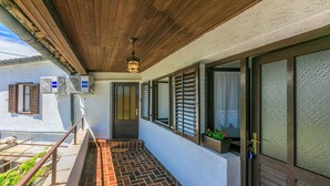 A covered balcony with a wooden ceiling, air conditioning units, and a door with shutters. - House Katica (Grizane)