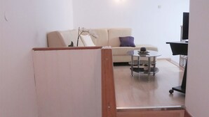A staircase leading to a living area with a sofa, a coffee table, and a TV.