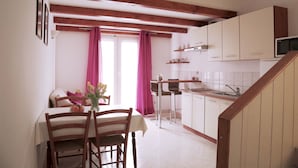 A kitchen with wooden beams, white cabinets, a dining table with chairs, and a kitchen island with bar stools.