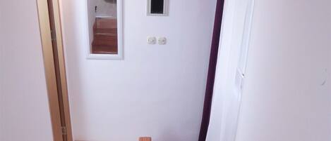 A staircase with wooden steps leading to a landing, a white door, a small window, and a potted orchid plant.