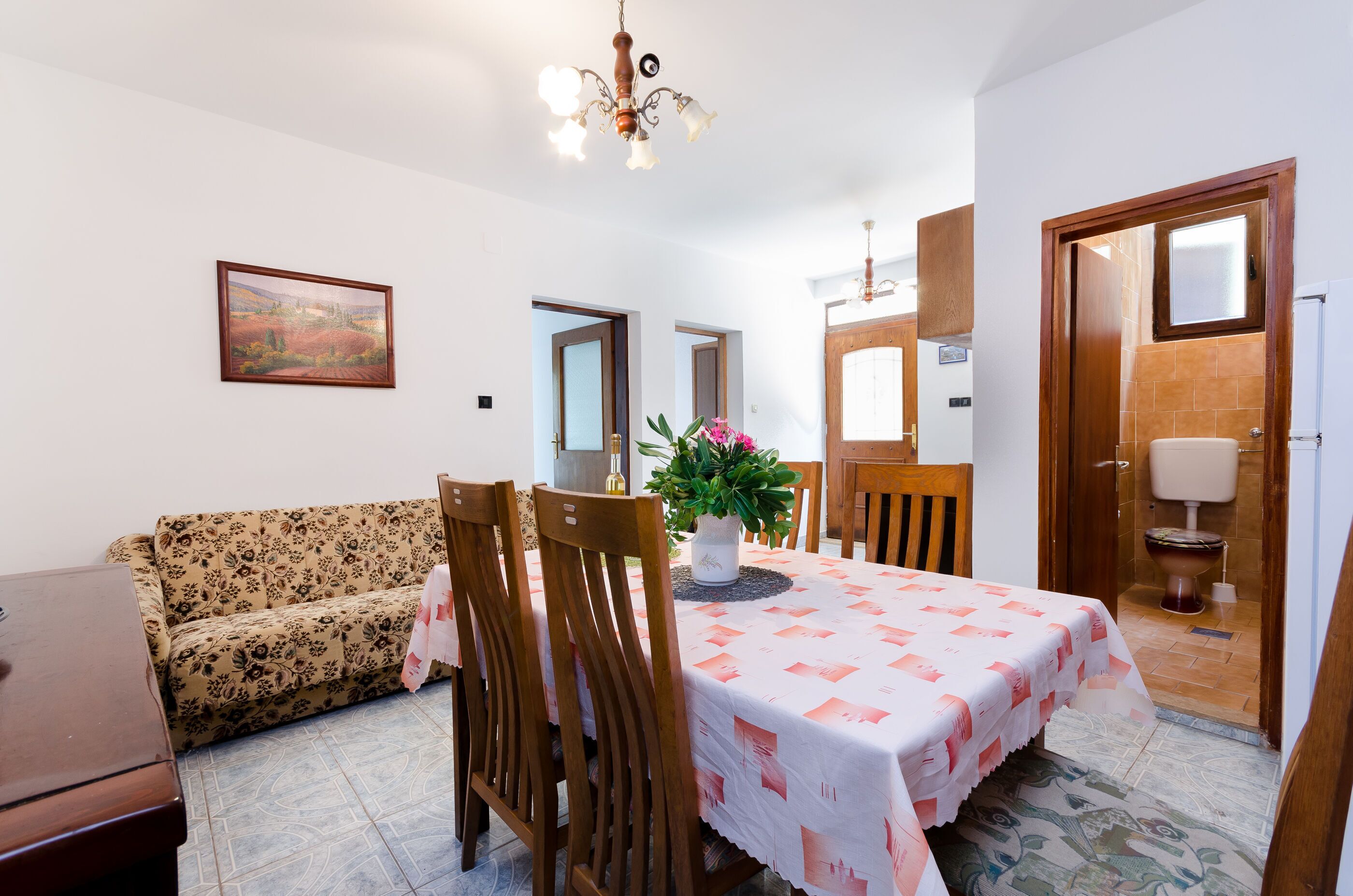 Un comedor con una mesa dispuesta para cuatro personas, un sofá y una planta en maceta.