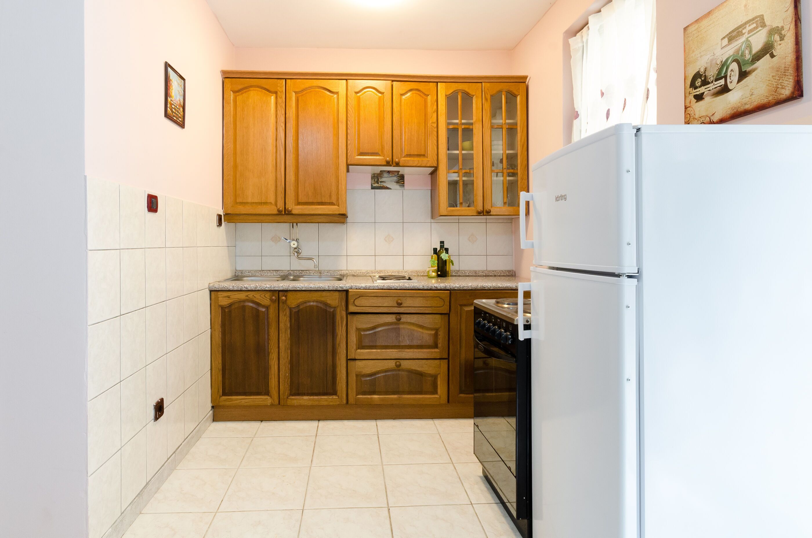 A kitchen with wooden cabinets, a white refrigerator, and a tiled backsplash.