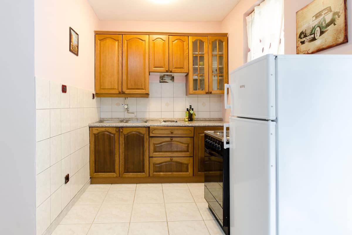 A kitchen with wooden cabinets, a white refrigerator, and a tiled backsplash.
