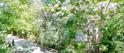 A garden with a stone wall, a metal table, and various plants.