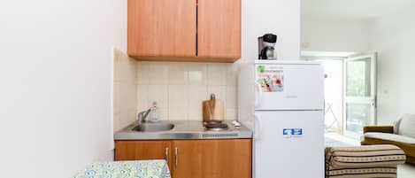 A compact kitchenette with a sink, stove, and a refrigerator.