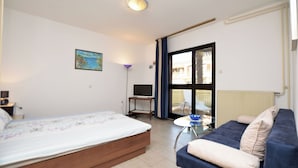 Een slaapkamer met een bed, een bank, een bureau met stoel, en een raam.