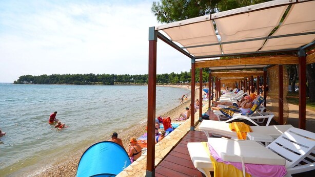 Een paviljoen aan het strand met ligbedden en een tent.