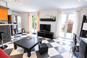 A modern living room with a black and white checkered floor, a flat-screen TV, a black coffee table, and a red sofa. - Apartment Sally (Cizici)