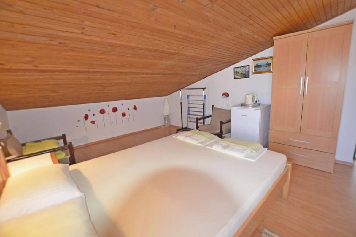 Un dormitorio con techo de madera, una cama, un armario, un escritorio y una silla.
