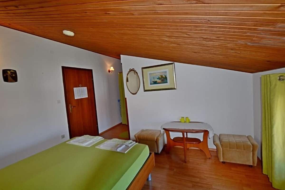 Una habitación pequeña con una cama, una mesa, una silla y una puerta.