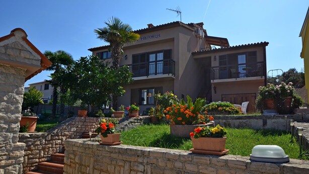 A building with a stone staircase, potted plants, and a clear blue sky. - Apartments and Rooms Viktorija (Pjescana uvala)