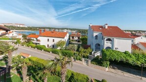 A coastal town with red-tiled buildings, a prominent white church, and a clear blue sky. - Apartments and Rooms Viktorija (Pjescana uvala)