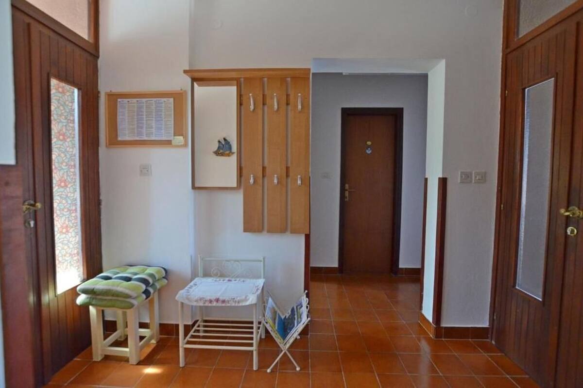 Un pasillo con puerta de madera, un banco, una mesita y un estante con revistas.