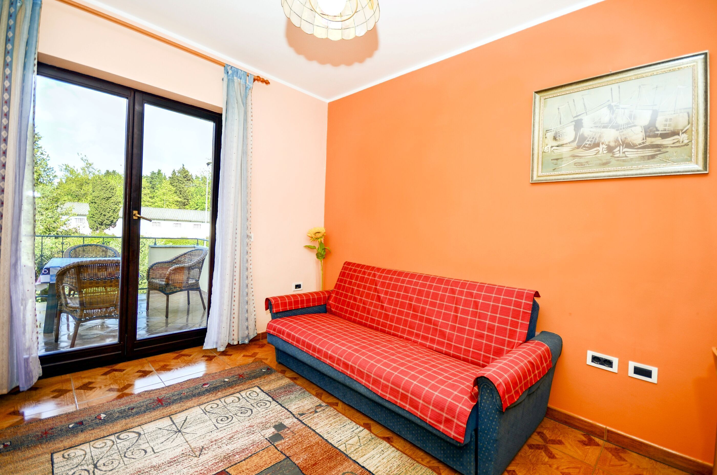 Ein Zimmer mit einer Couch, einem gemusterten Teppich, einer Schiebetür und einem gerahmten Bild an der Wand.