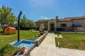 Una casa de piedra con techo de tejas, piscina y un camino de jardín.