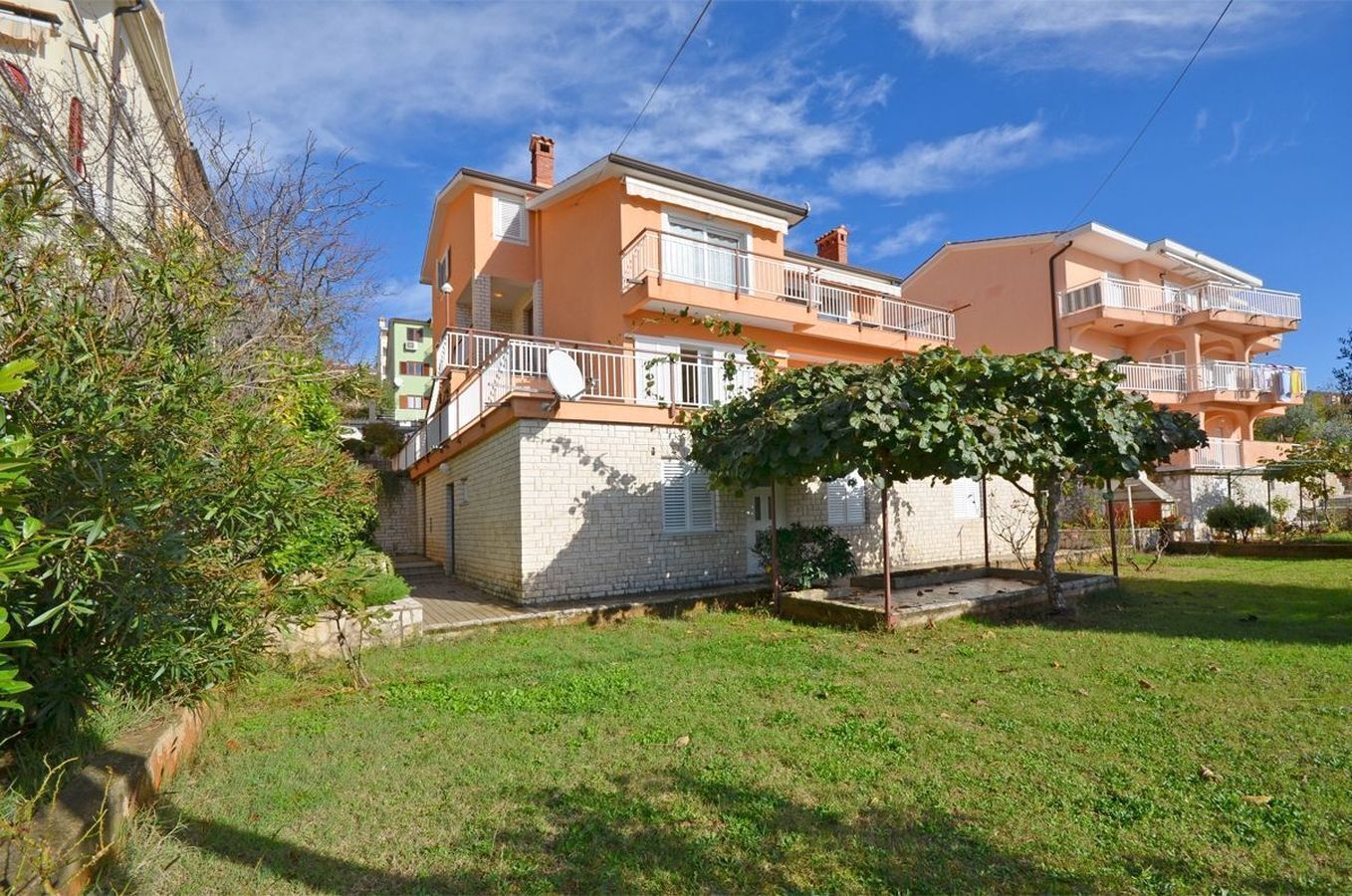 A two-story residential building with a balcony and a small garden area.