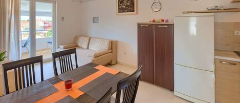 A compact living space with a dining area, kitchenette, and a sofa.