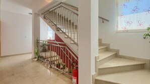 Un escalier avec une rampe en métal, un extincteur et des plantes en pot.