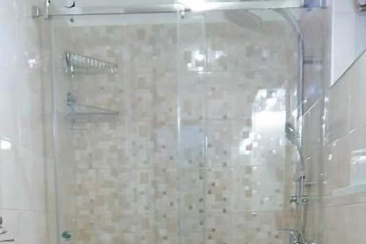A bathroom with a glass shower enclosure, a white sink, and a patterned shower curtain.
