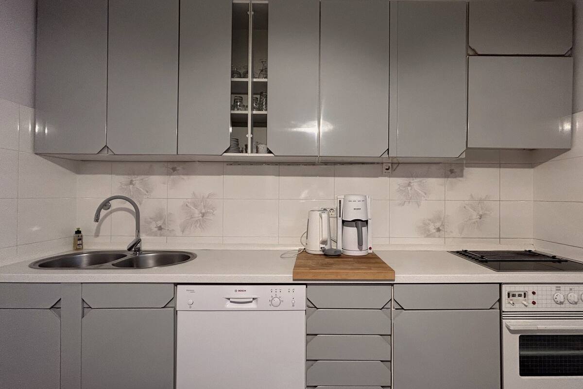 A kitchen with grey cabinets, a Bosch dishwasher, a coffee maker, and a stove.
