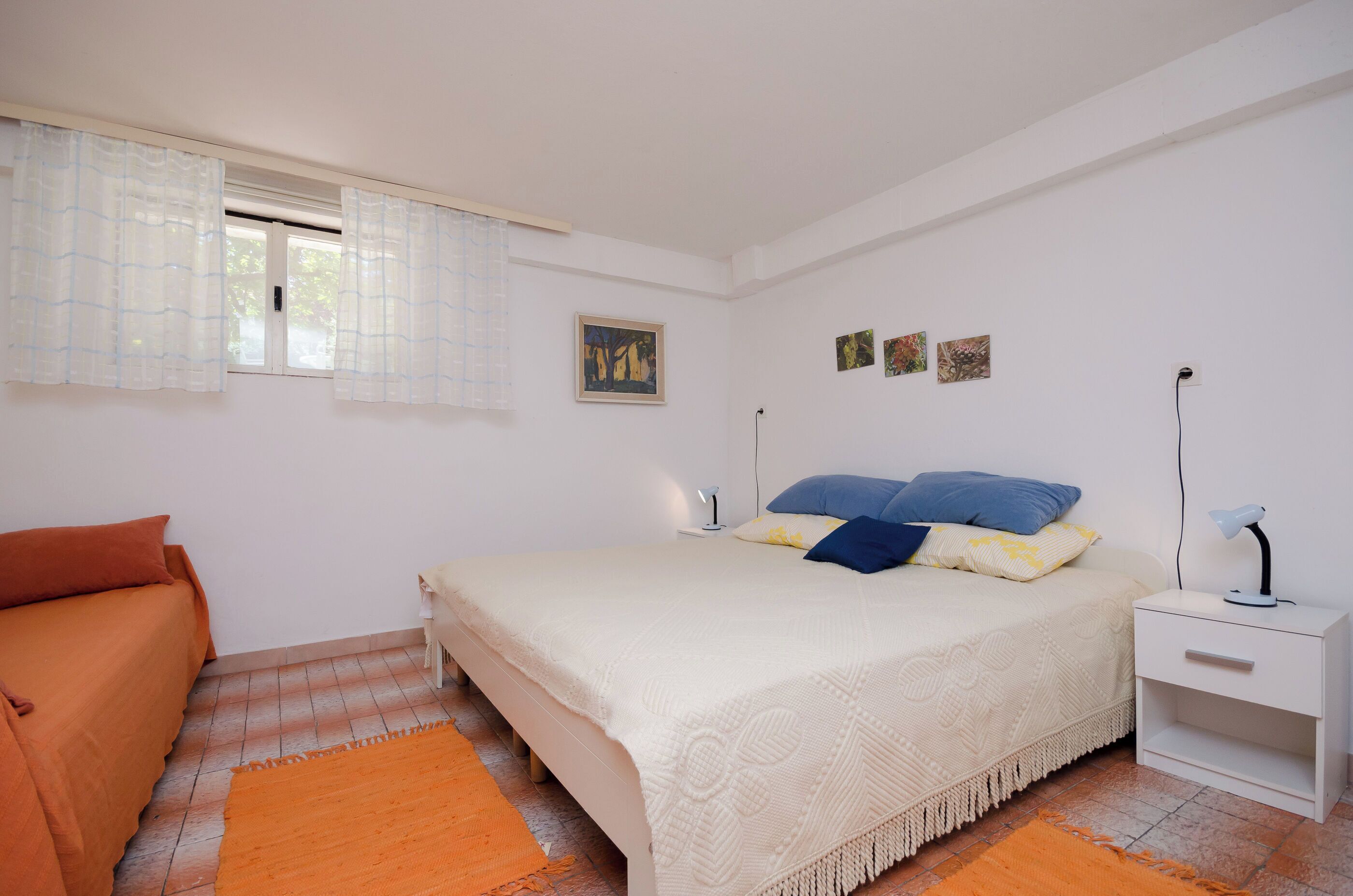 A bedroom with a bed, nightstand, and a window with curtains.