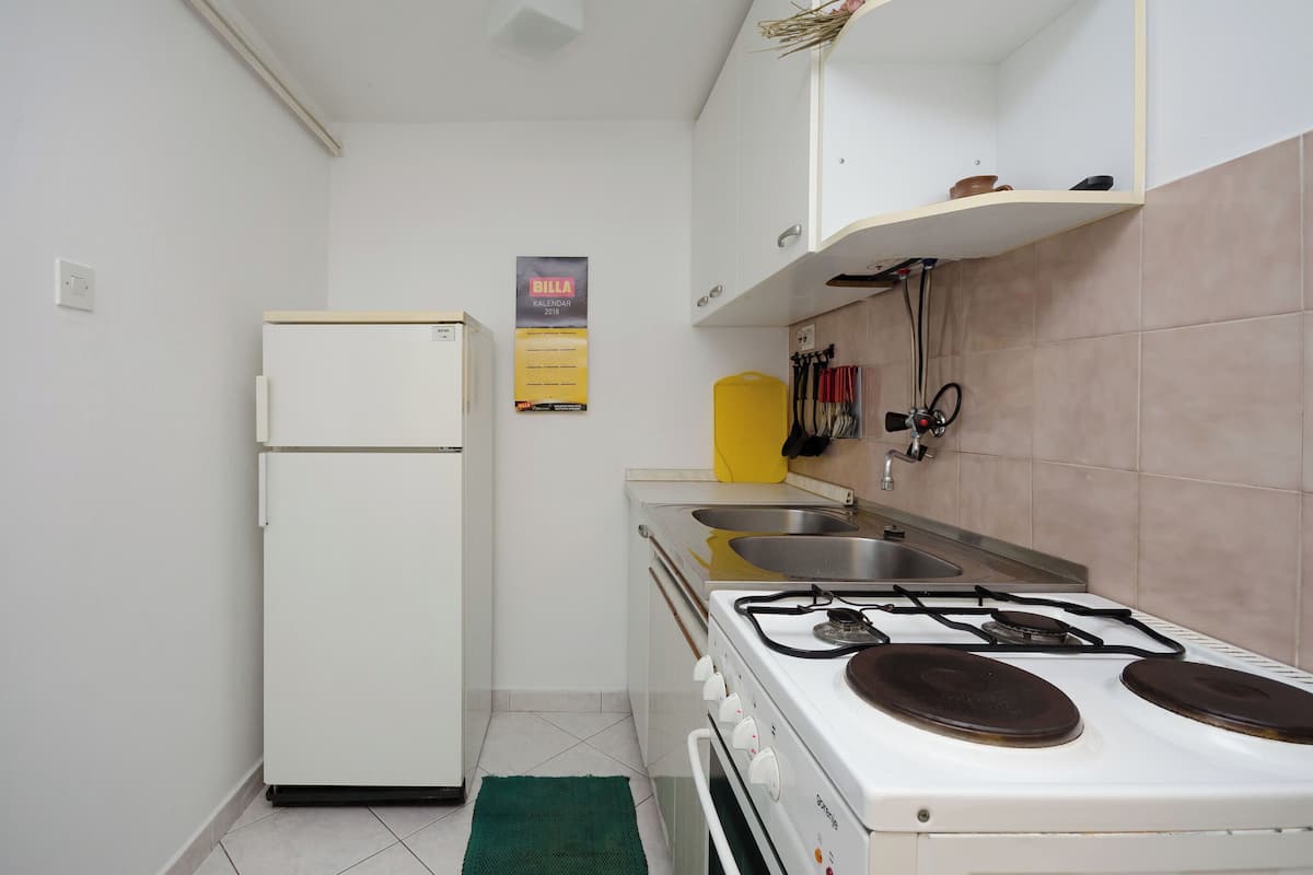 Une cuisine de taille réduite, avec un réfrigérateur blanc, une cuisinière à gaz et un évier.