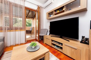 Un soggiorno moderno con televisore a schermo piatto, mobile TV in legno e zona pranzo con tavolo e sedie.