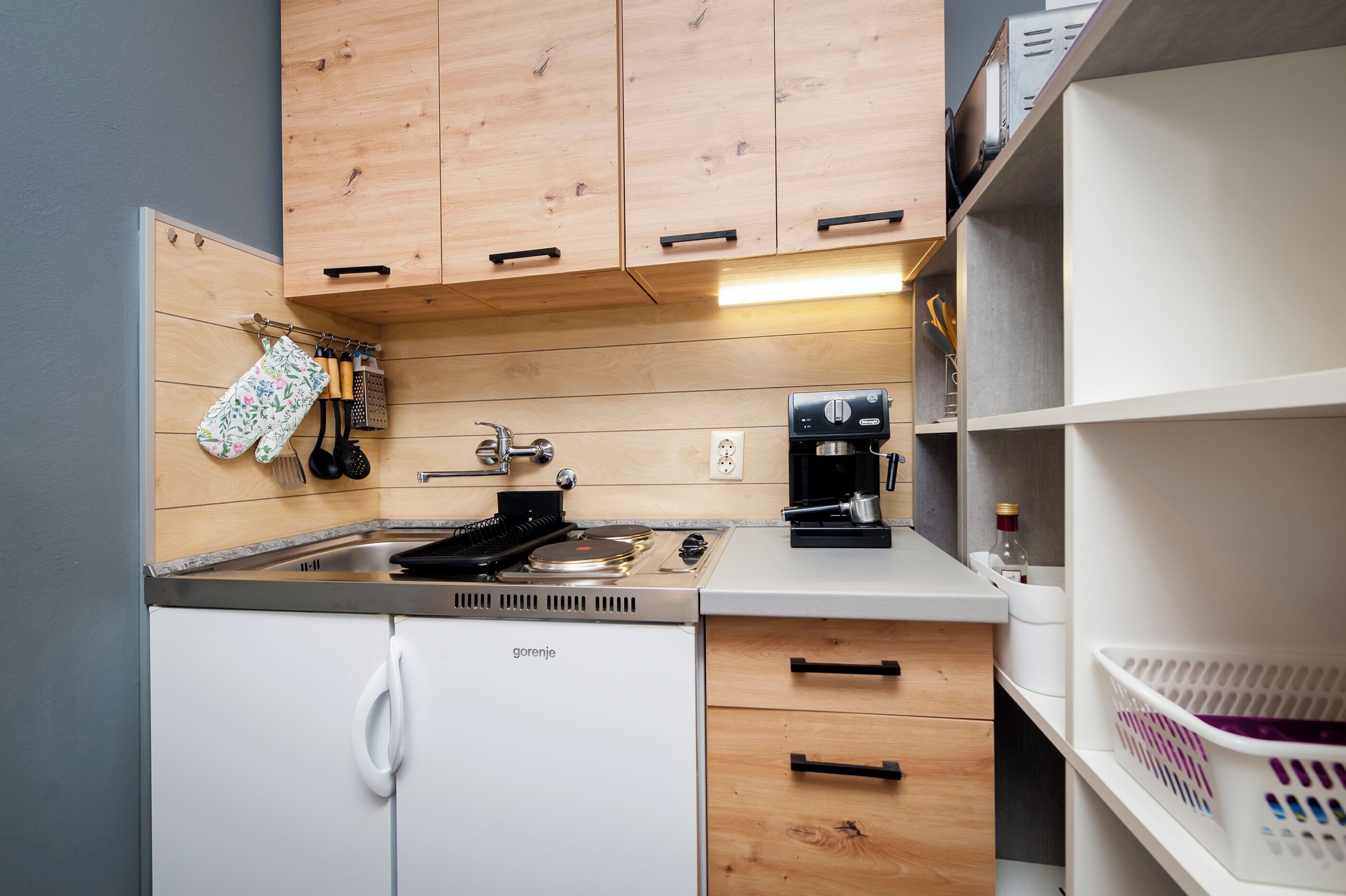 A compact kitchen with wooden cabinets, a built-in stove, and a coffee maker.