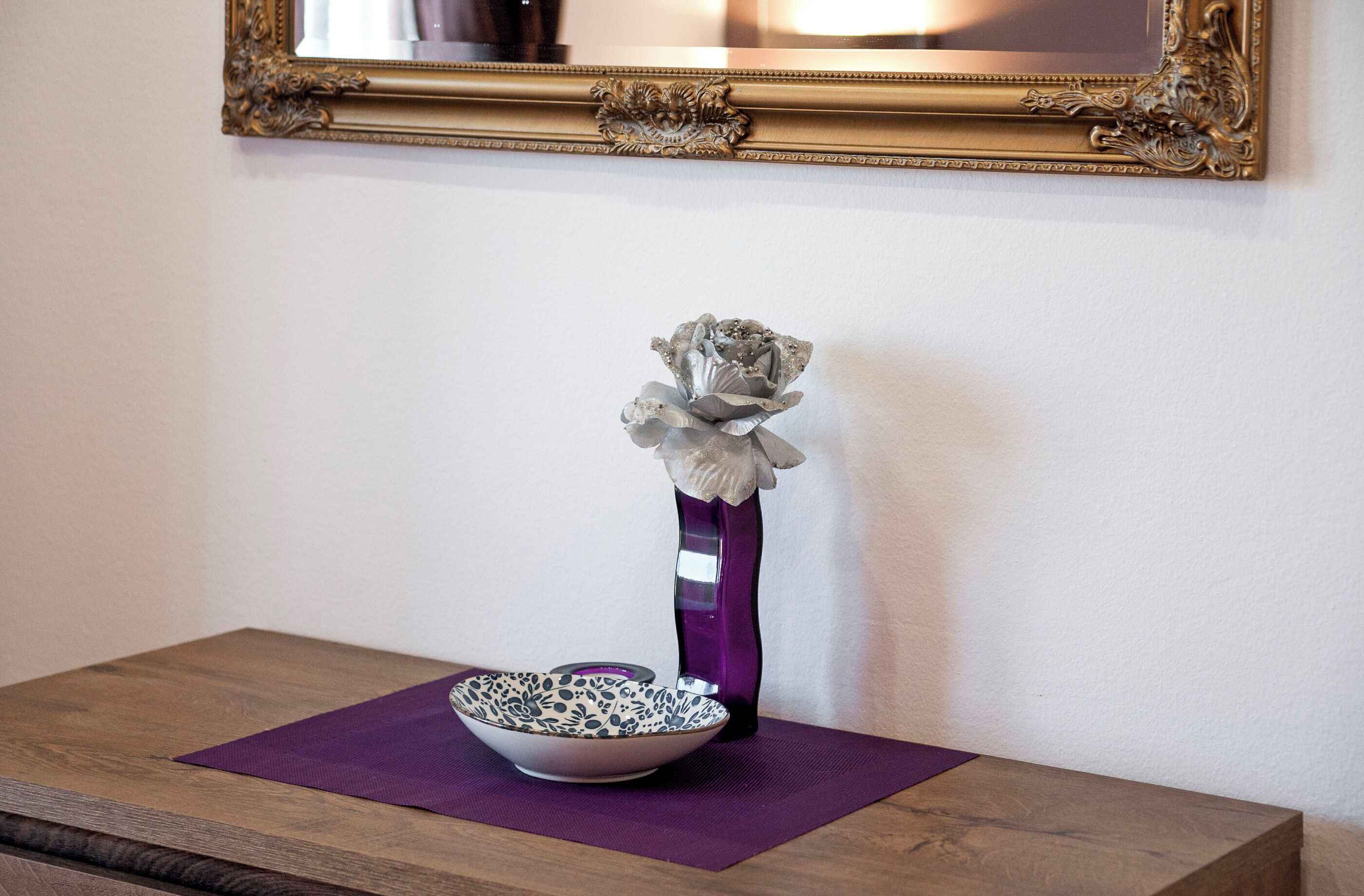 Une table avec un bol et un vase posés sur un set de table violet.