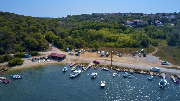 A marina with boats docked, a sandy beach, and a hillside with buildings. - Apartments Davorka (Banjole)