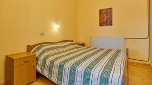 A bedroom with a bed, a nightstand, a wall-mounted light, a radiator, and a poster on the wall. - Apartments Davorka (Banjole)