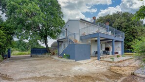 Ein zweistöckiges Haus mit Balkon, Treppe und einer Steinterrasse.