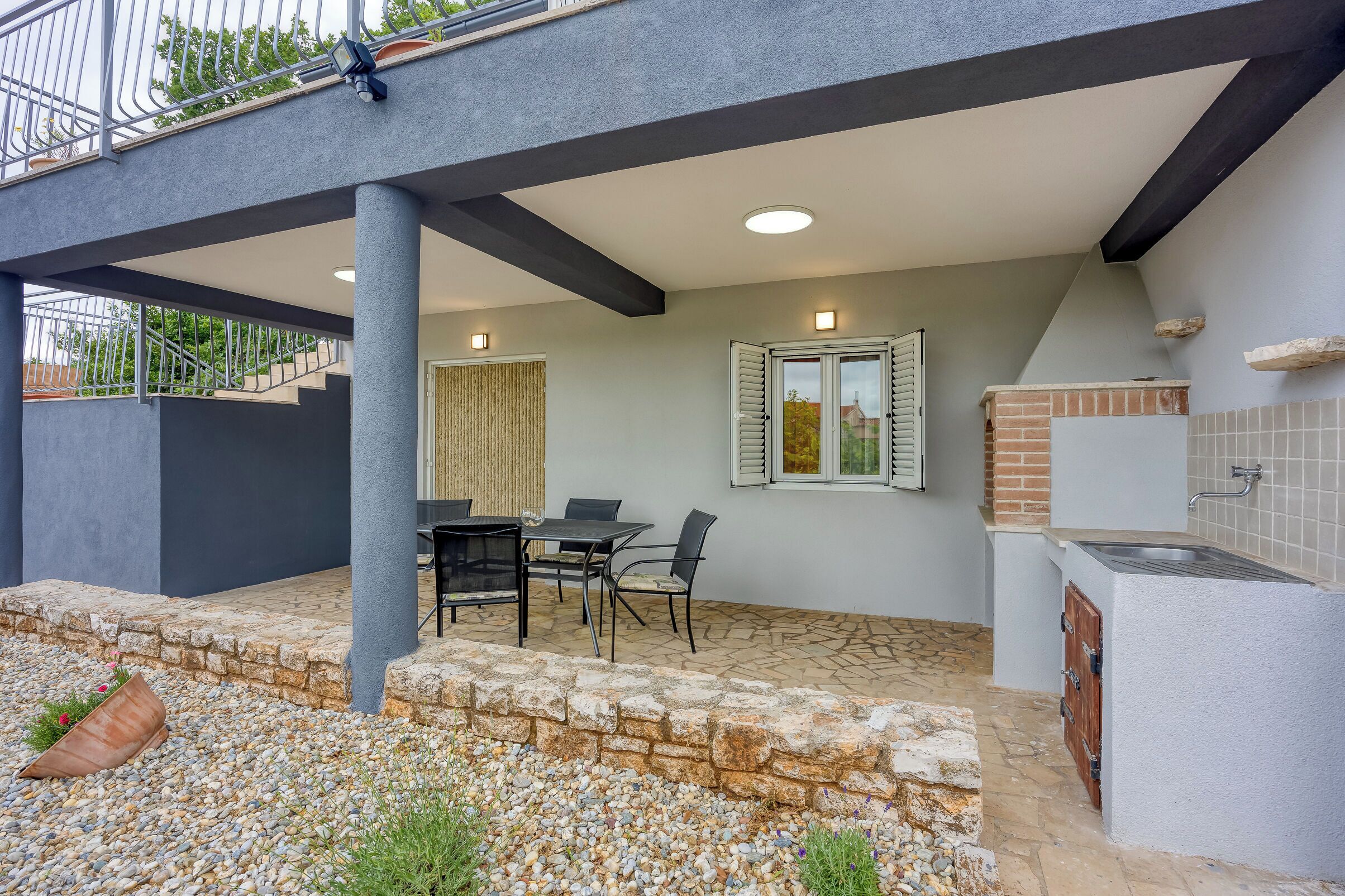 An outdoor patio with a table and chairs, a stone wall, and a small brick oven.