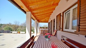 A covered outdoor seating area with a checkered tablecloth, wooden benches, and a potted plant. - Apartment Bungalov (Rovinj)