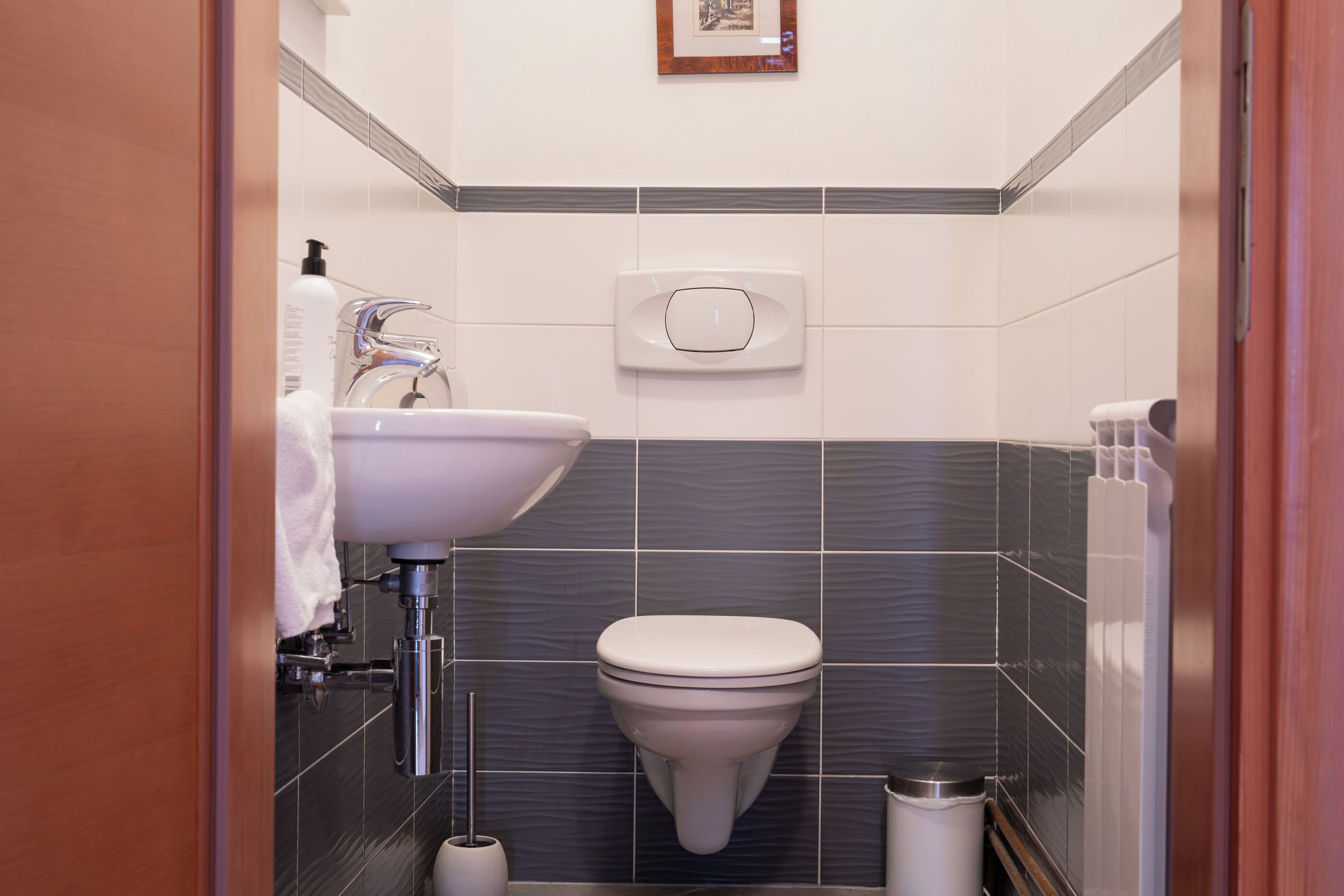 A modern bathroom with a white sink, a toilet, and a hand dryer.