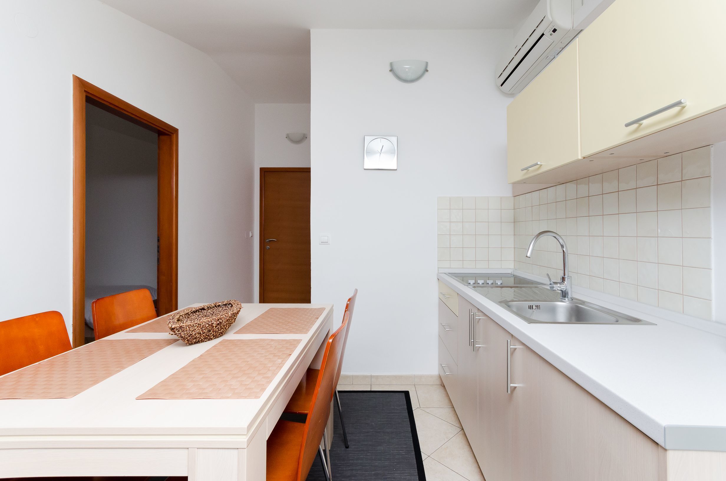 A compact kitchen with a sink, cabinets, and a dining area with a table and chairs.