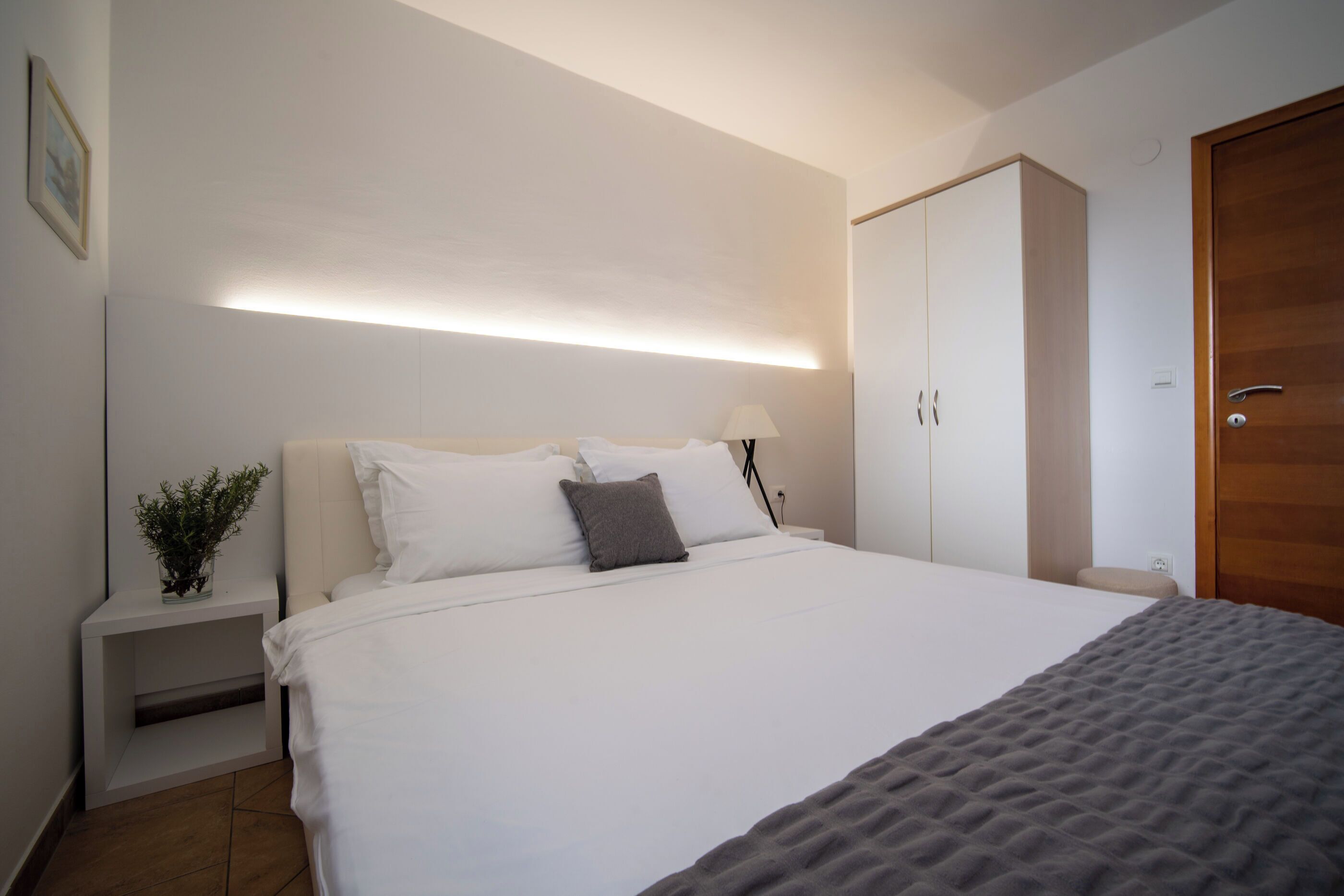 A neatly arranged bedroom with a bed, bedside table, lamp, wardrobe, and a door.