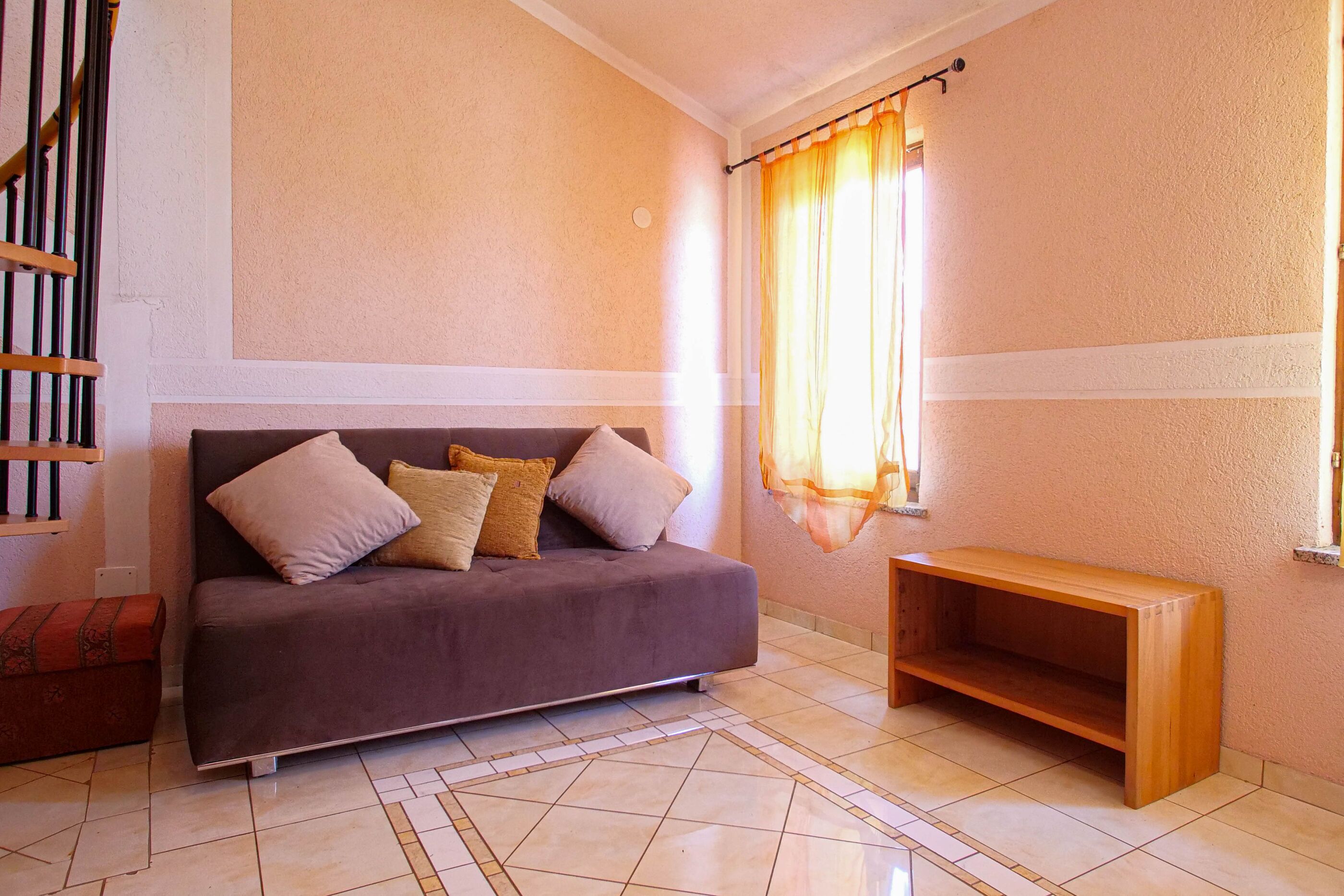 A living room with a sofa, a wooden bench, and a patterned rug.