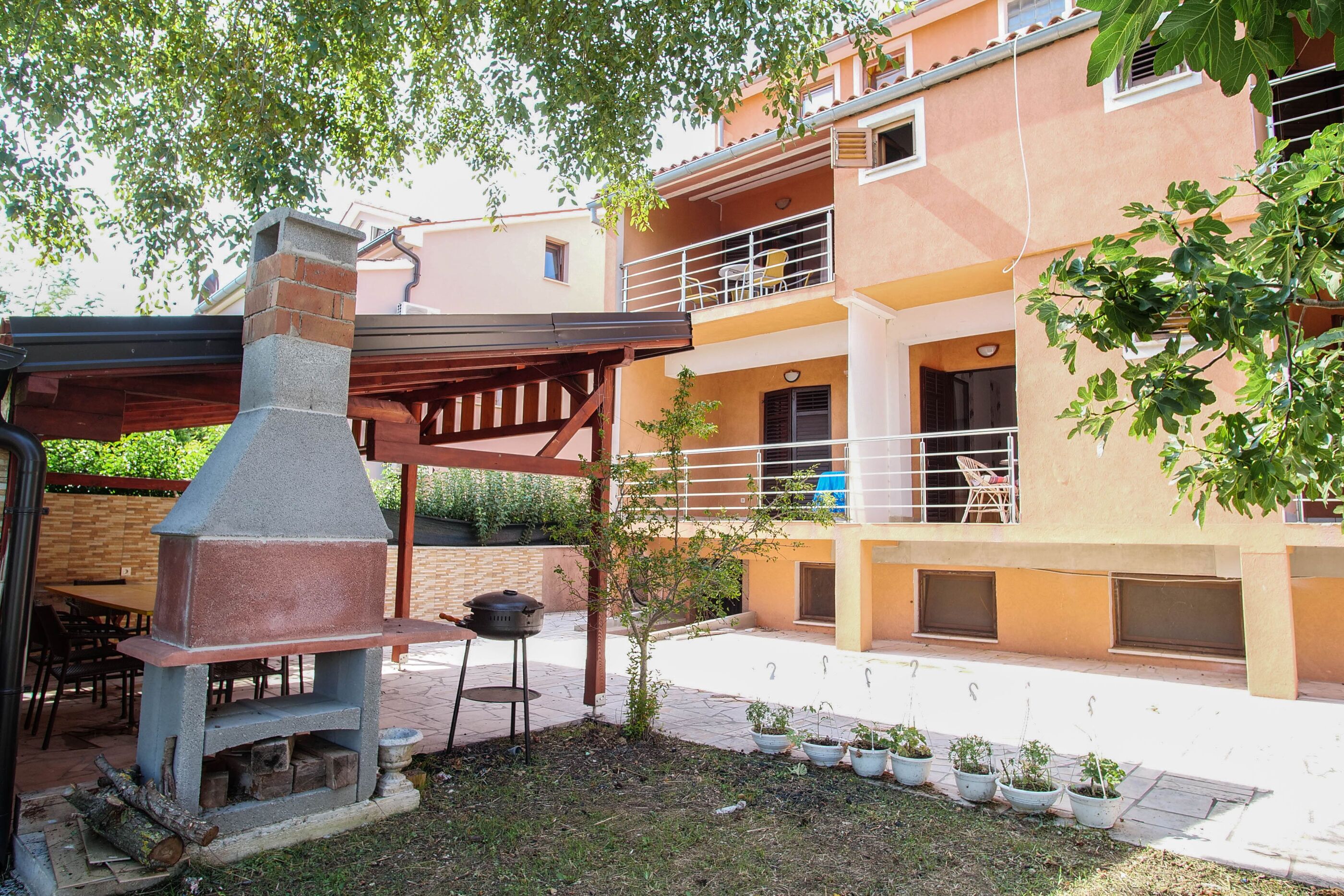 A patio area with a barbecue grill, a pergola, and potted plants.