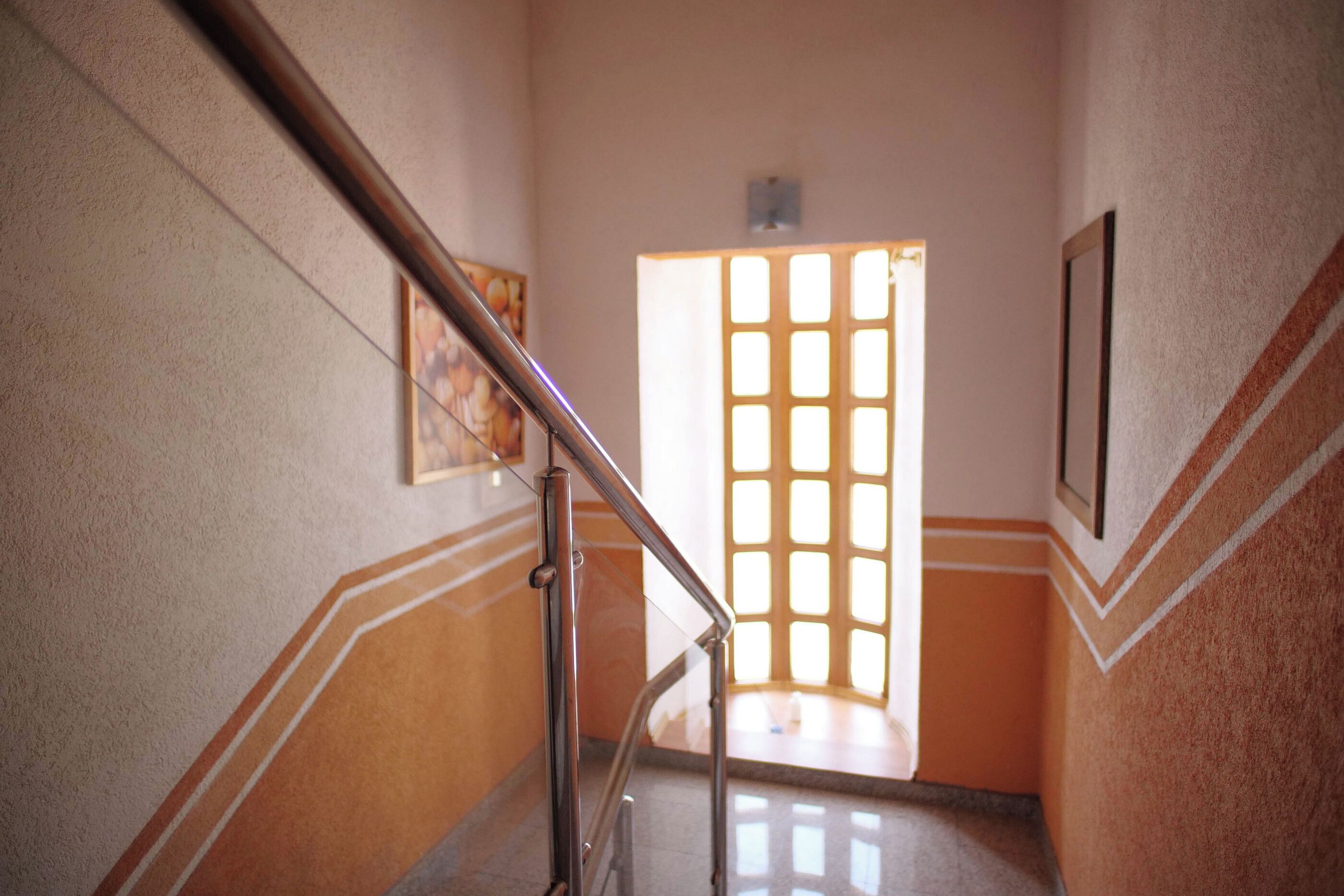 Un couloir avec un escalier, une porte dotée d’une fenêtre et un tableau encadré accroché au mur.