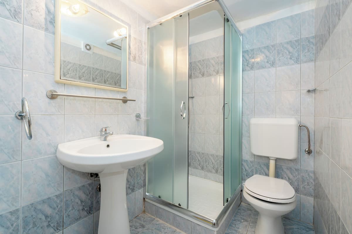 A bathroom with a pedestal sink, a glass-enclosed shower, and a toilet.