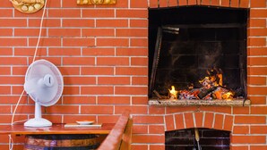 A brick fireplace with a fan and decorative items on the wall. - House Bruno (Pula)