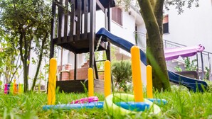 A grassy area with playground equipment including a slide and swings. - House Bruno (Pula)
