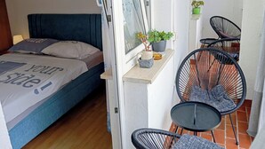 A bedroom with a bed, a window, a small table with chairs, and a potted plant. - Apartment Vladimir (Medulin)