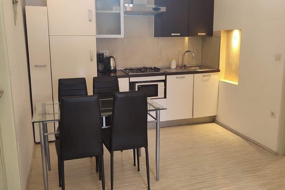 A compact kitchen with a dining area, featuring a stove, sink, and cabinets.