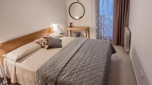 A neatly arranged bedroom with a bed, bedside table, lamp, and a mirror. - Apartments Cerin (Rovinj)