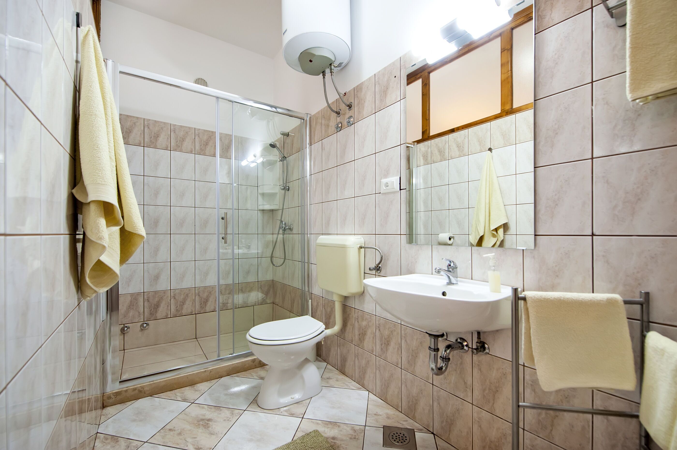 A modern bathroom with a glass-enclosed shower, a toilet, a sink, and a mirror.