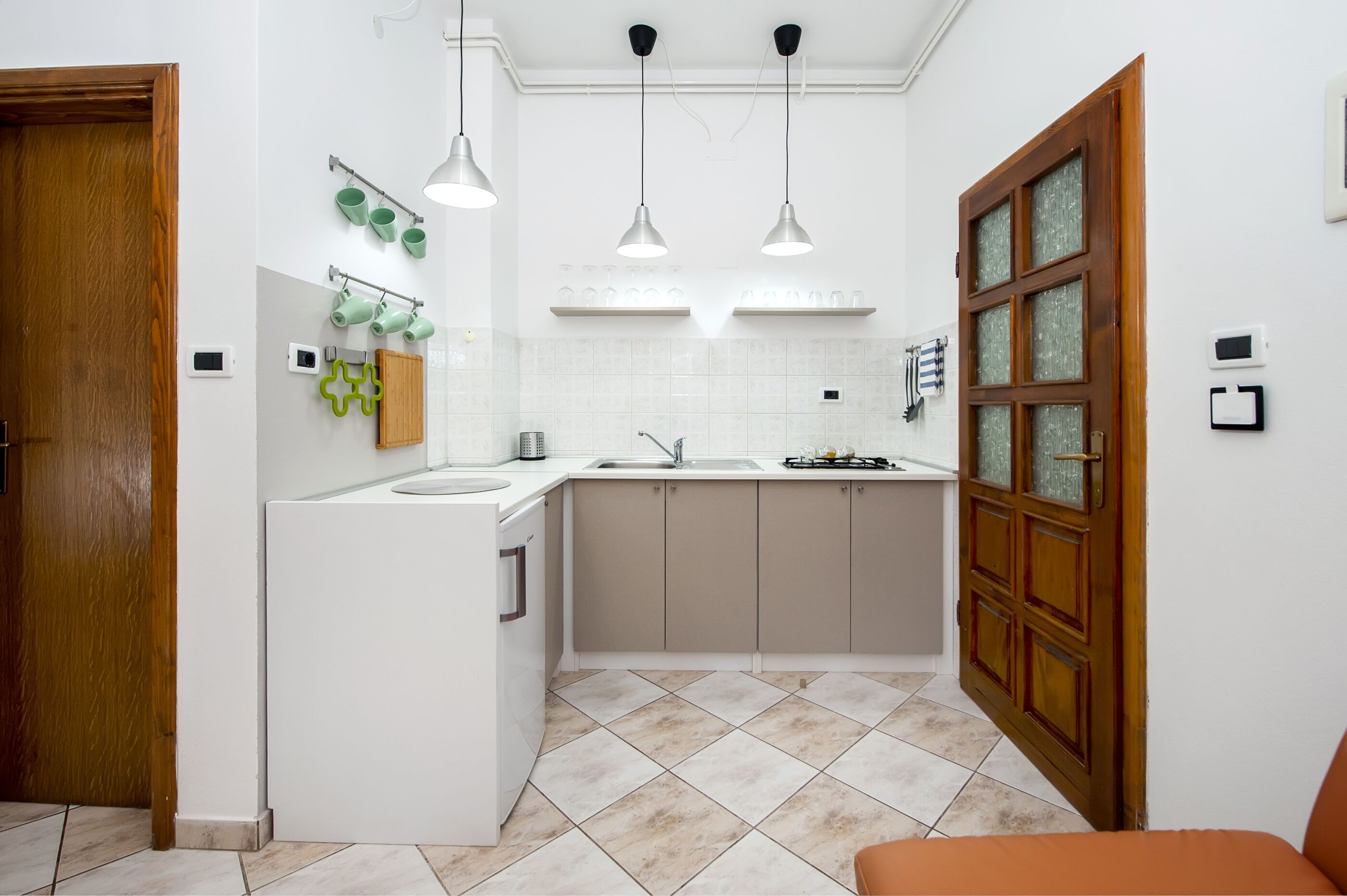 A compact kitchen with a sink, cabinets, and hanging lights.