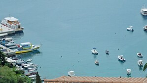 A marina with various boats docked, a red submarine, and a white boat with a blue canopy. - Apartments Elide (Rabac)